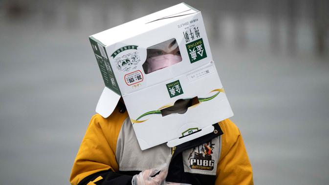Seorang anak mengenakan kotak kardus di kepalanya untuk melindungi diri dari wabah virus corona di stasiun Kereta Api Shanghai di Shanghai pada 13 Februari 2020. Awal tahun 2020 ini, masyarakat dunia dikejutkan dengan hadirnya virus corona COVID-19 yang mematikan asal Wuhan, China. (NOEL CELIS/AFP)