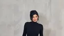Kylie Jenner tampil dengan mini dress hitam lengan panjang model turtle neck, dipadukan skirt model tetesan air yang menarik perhatian. [@winmetawain]