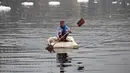 Seorang pria mendayung rakitnya sambil mengumpulkan bahan-bahan daur ulang dekat potongan busa tercemar yang mengambang di Sungai Yamuna, New Delhi, India, 26 Desember 2021. Lapisan busa beracun melapisi sungai yang dianggap suci oleh umat Hindu, Sungai Yamuna. (Sajjad HUSSAIN/AFP)