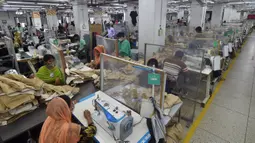 Para buruh bekerja pada stasiun mereka yang dipisahkan oleh sekat sebagai tindakan pencegahan terhadap penularan virus corona COVID-19 di pabrik garmen Civil Engineers Limited, Dhaka, Bangladesh, 17 Agustus 2021. (Munir UZZAMAN/AFP)