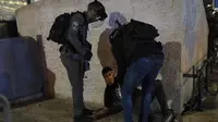 Polisi Israel menahan pemuda Palestina di Gerbang Damaskus ke Kota Tua Yerusalem di kompleks Masjid Al-Aqsa (7/6/2021). Layanan ambulans Bulan Sabit Merah Palestina mengatakan 88 orang Palestina yang terluka dibawa ke rumah sakit setelah terkena peluru logam berlapis karet. (AP Photo/Mahmoud Illean)