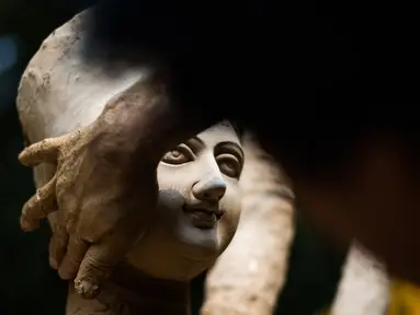 Seorang perajin membuat patung dewi Durga menjelang festival 'Durga Puja' di sebuah workshop di New Delhi, India, Rabu (14/10/2020). Durga Puja merupakan festival tahunan di Asia Selatan untuk memuja dewi Durga dari agama Hindu. (Photo by Jewel SAMAD / AFP)