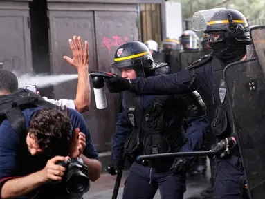 Polisi anti huru-hara menyemprotkan gas ke demonstran dan para fotografer saat terjadi bentrokan di Paris, Prancis (23/5). Para pekerja layanan publik Prancis melakukan pemogakan dan meluas menjadi aksi protes. (AP/Christophe Ena)