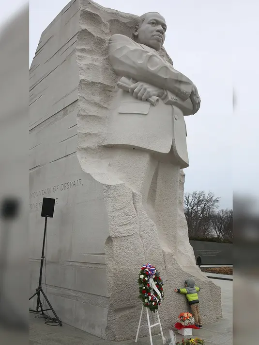 Seorang bocah memeluk patung Martin Luther King Jr saat 'Hari Martin Luther King Jr' MLK adalah tokoh AS yang menyuarakan tentang perdamaian dunia. (Joe Raedle / Getty Images / AFP)