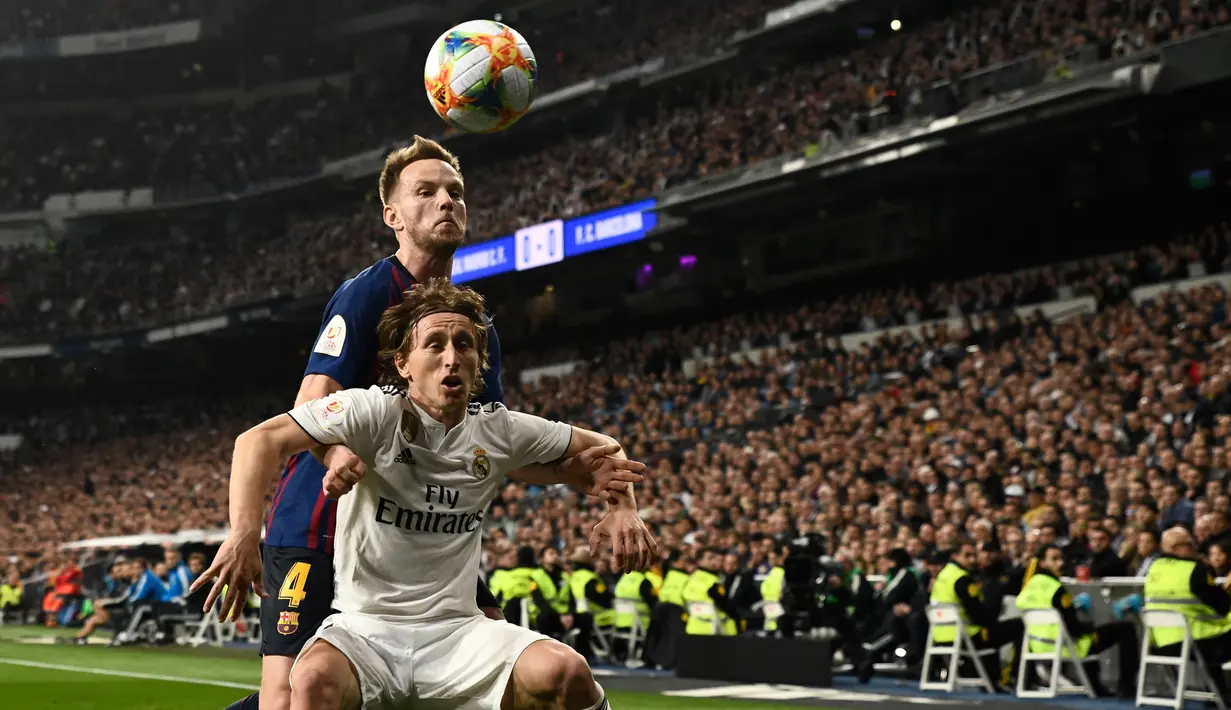Gelandang Barcelona, Ivan Rakitic berebut bola dengan pemain Real Madrid, Luka Modric pada laga leg kedua semifinal Copa del Rey di Stadion Santiago Bernabeu, Rabu (27/2). Barcelona merebut tiket final Copa del Rey usai menang 3-0. (OSCAR DEL POZO / AFP)