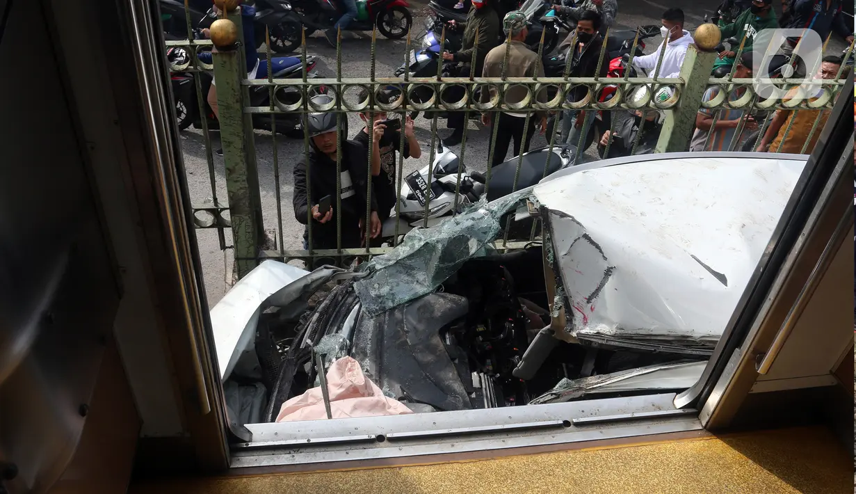 Warga mengambil gambar mobil Honda Mobilio yang tertabrak KRL Commuterline KA 1077 (Bogor-Jakarta Kota) di kawasan Rawageni, Ratu Jaya, Cipayung, Depok, Jawa Barat, Rabu (20/4/2022). Kecelakaan di perlintasan sebidang itu menyebabkan terganggunya perjalanan KRL. (merdeka.com/Arie Basuki)