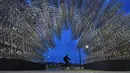 Seorang pria mengendarai sepeda melewati instalasi seni seniman China Ai Weiwei yang berjudul 'Forever Cycles' di Rio de Janeiro, Brasil, Senin (19/8/2019). Instalasi Ai Weiwei ini akan dibuka pada 21 Agustus 2019. (CARL DE SOUZA/AFP)