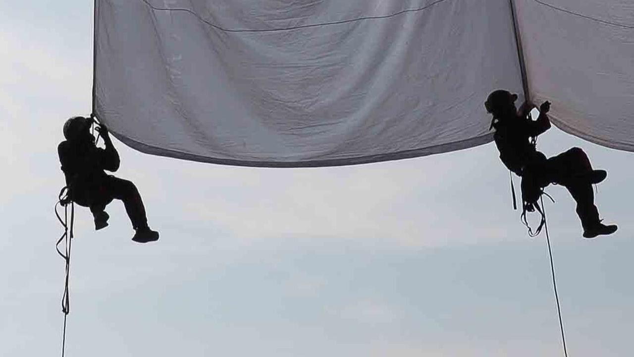 Bendera raksasa itu dikaitkan dengan tali karmantel pada mulut Goa Sigugula di Tebing Arpam, Klapanunggal.