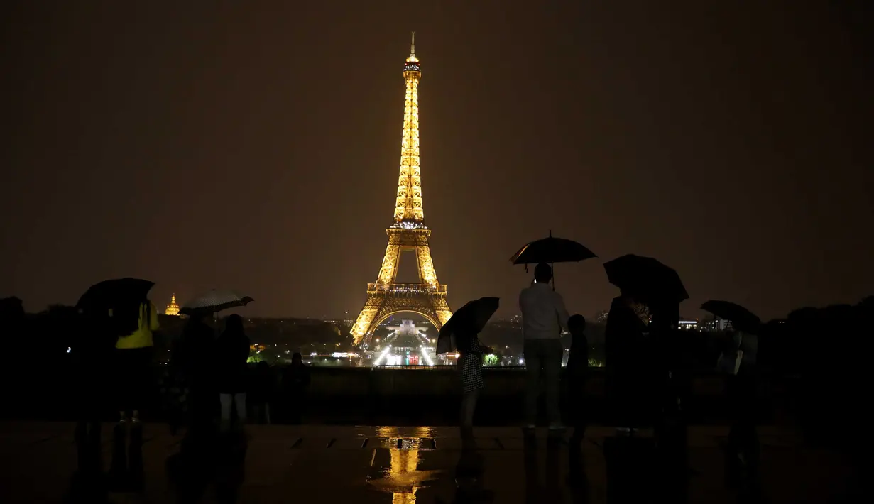 Sejumlah wisatawan menikmati pemandangan Menara Eiffel yang diterangi lampu dari Trocadero Plaza di Paris, Prancis (1/9).( AFP Photo/Ludovic Marin)