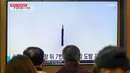 Orang-orang duduk di dekat layar televisi yang menayangkan siaran berita dengan rekaman file uji coba rudal Korea Utara, di sebuah stasiun kereta api di Seoul, Korea Selatan, Minggu (9/10/2022). Sejumlah pejabat Jepang mengatakan Korea Utara menembakkan dua rudal balistik pada Minggu pagi. (Photo by ANTHONY WALLACE / AFP)