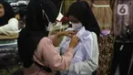 Calon pembeli mencoba seragam sekolah kepada anaknya di Pasar Kebayoran Lama, Jakarta, Jumat (8/7/2022). Menjelang dimulainya tahun ajaran baru, para orang tua disibukkan berbelanja baju seragam dan perlengkapan sekolah untuk anak mereka. (Liputan6.com/Angga Yuniar)
