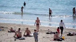 Orang-orang berjemur dan berenang di pantai Catalans (Plage des Catalans) di Marseille, Prancis Selatan, (17/4). Pantai ini memiliki dua lapangan voli pantai di mana beberapa kompetisi internasional diselenggarakan. (AFP Photo/Bertrand Langlois)