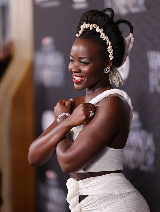 Lupita Nyong'o berpose saat menghadiri pemutaran perdana film Black Panther: Wakanda Forever" di Dolby Theatre di Los Angeles pada Rabu, 26 Oktober 2022. Rambut brunette-nya ditata dengan twist updo yang beraksen dengan ikat kepala yang terbuat dari kerang. (Jesse Grant/Getty Images for Disney/AFP)