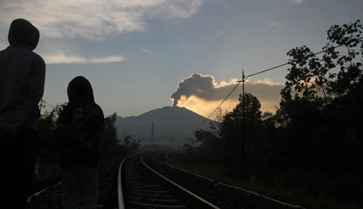 Warga melihat Gunung Raung mengeluarkan awan panas yang terlihat dari Kabupaten Jember, Jawa Timur, Minggu (12/7/2015). Gunung Raung terus menunjukkan aktivitas vulkaniknya dan menyebabkan terjadi hujan abu tipis di sejumlah wilayah. (AFP PHOTO)