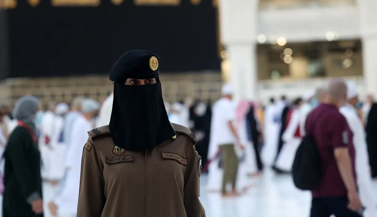 Seorang polisi wanita Saudi berjaga-jaga saat jemaah mengelilingi Ka'bah pada rangkaian ibadah haji di Masjidil Haram, Makkah, Selasa (20/7/2021). Kini, para personel perempuan bergabung dengan rekan-rekan pria mereka dalam menjaga kota suci selama musim haji. (Fayez Nureldine / AFP)