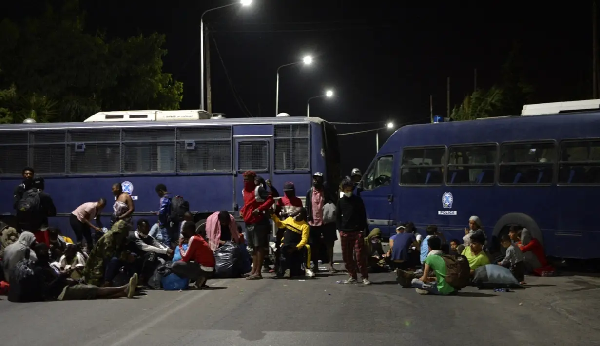 Pengungsi dan migran mencoba mencapai pelabuhan Mytilene saat polisi memblokir jalan saat terjadi kebakaran di kamp pengungsi Moria di timur laut pulau Aegean Lesbos, Yunani, Rabu (9/9/2020). Otoritas Yunani belum dapat mengungkap penyebab pasti terjadinya kebakaran. (AP Photo/Panagiotis Balaskas)