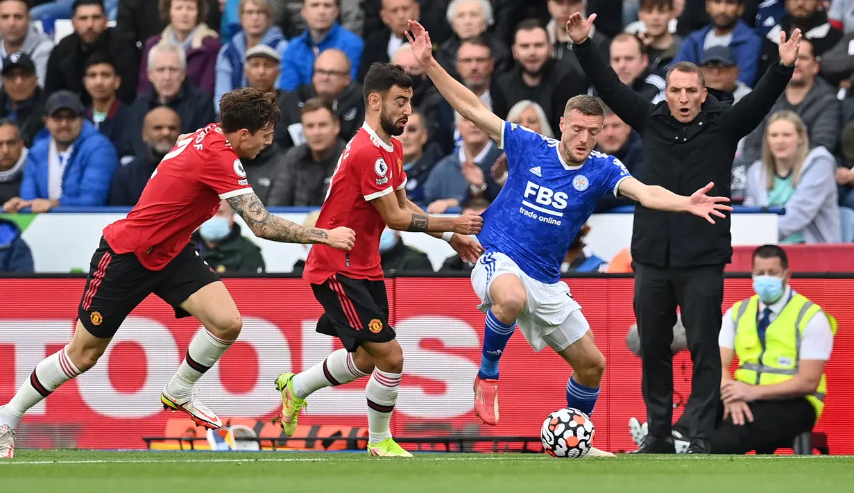 Striker Leicester City, Jamie Vardy (kanan) berusaha melepaskan diri dari kawalan dua pemain Manchester United, Bruno fernandes (tengah) dan Victor Lindelof pada laga pekan ke-8 Liga Inggris 2021/2022 di King Power Stadium, Leicester (16/10/2021). Jamie Vardy total mencetak 6 gol dan 4 assist dari 18 laga bersama Leicester City saat menghadapi Manchester United di semua ajang. Gol terakhirnya terjadi pada pekan ke-8 Liga Inggris 2021/2022 saat Leicester City menang 4-2. (AFP/Lindsey Parnaby)