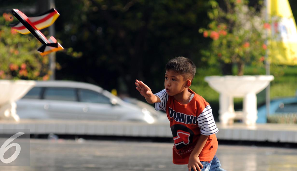 Seorang anak berusaha menerbangkan pesawat mainan saat bermain di Lapangan Monumen Tugu Pancasila TMII, Jakarta, Jumat (8/7). TMII masih menjadi lokasi favorit warga menghabiskan libur hari raya. (Liputan6.com/Helmi Fithriansyah)