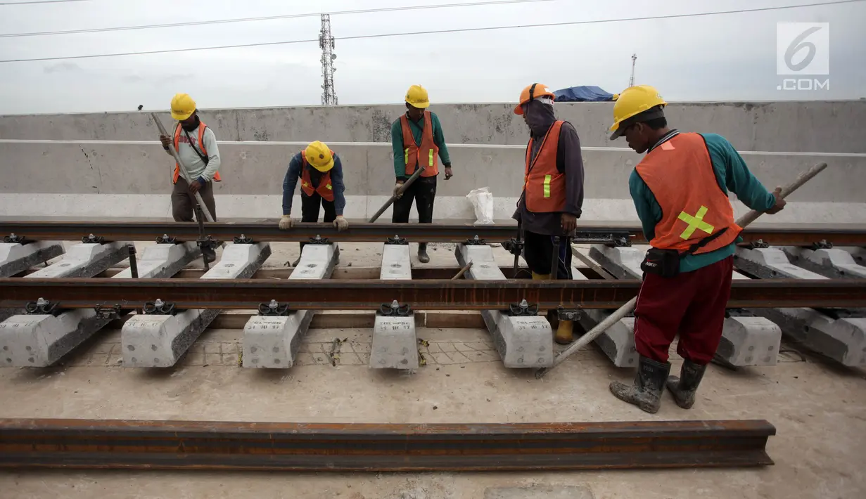 Pekerja memasang rel di Depo LRT, Kelapa Gading, Jakarta Utara, Kamis (25/1). Rencananya, LRT akan mulai diuji coba pada Mei mendatang. (Liputan6.com/Arya Manggala)