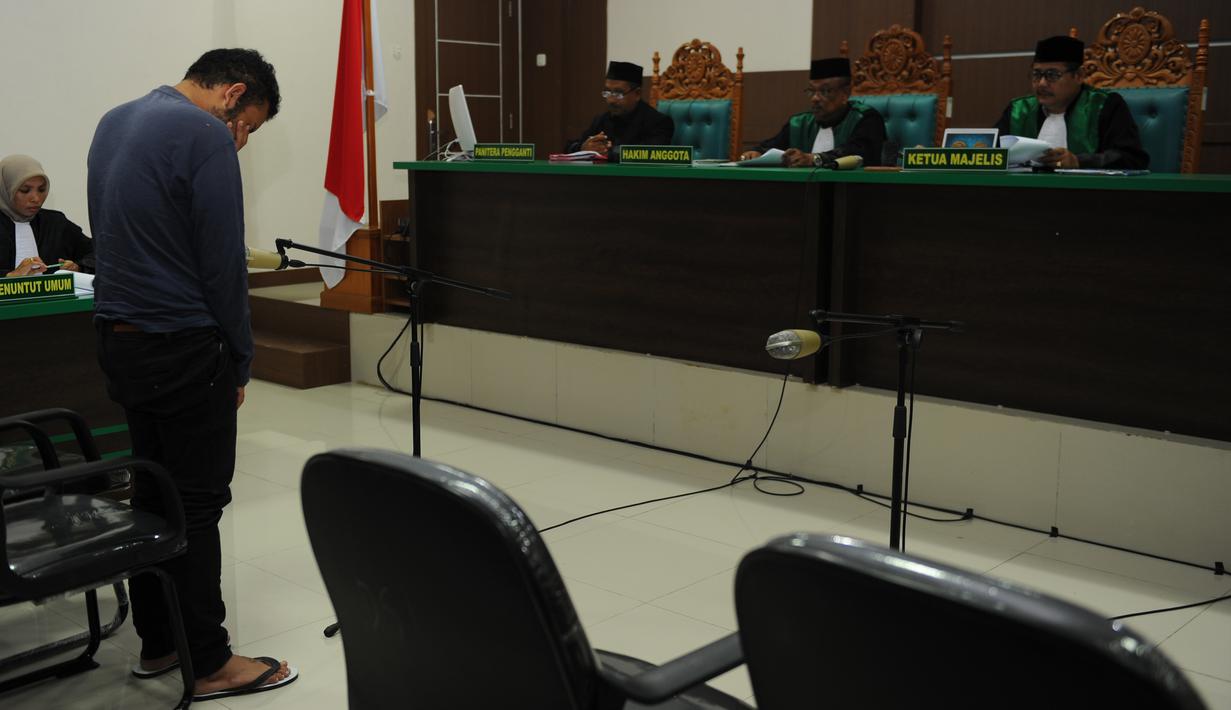 Terdakwa pasangan sejenis (gay) di Aceh saat menghadiri persidangannya di pengadilan syariah di Banda Aceh (17/5). Terdakwa dinyatakan melanggar Pasal 63 ayat 1 Qanun Aceh Nomor 6 tentang Hukum Jinayat. (AFP/Chaideer Mahyuddin)