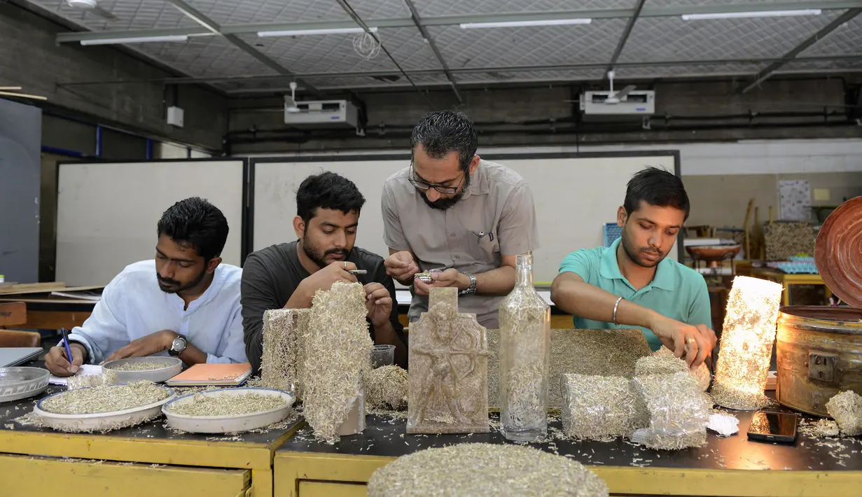 Desainer National Institute of Design (NID), Pravinsinh Solanki (dua kanan) membimbing muridnya saat membuat karya seni dari uang kertas pecahan 500 dan 1.000 Rupee di Ahmedabad, India (26/4). (AFP PHOTO/SAM PANTHAKY)
