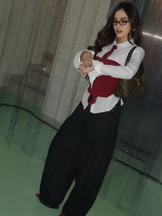 Wajahnya dipulas blush on pink dan lipstik nude ombre. Rambut panjangnya terurai bergaya wavy dengan poni belah dua.  [@mahaliniraharja]