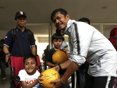 Pelatih Timnas Indonesia U-23, Indra Sjafri, memberikan bola kepada anak-anak yang datang ke Stadion Madya, Jakarta, Rabu (13/3). Sejumlah anak dari Yayasan Rumah Harapan Indonesia datang menemui Timnas U-23 (Bola.com/Vitalis Yogi Trisna)