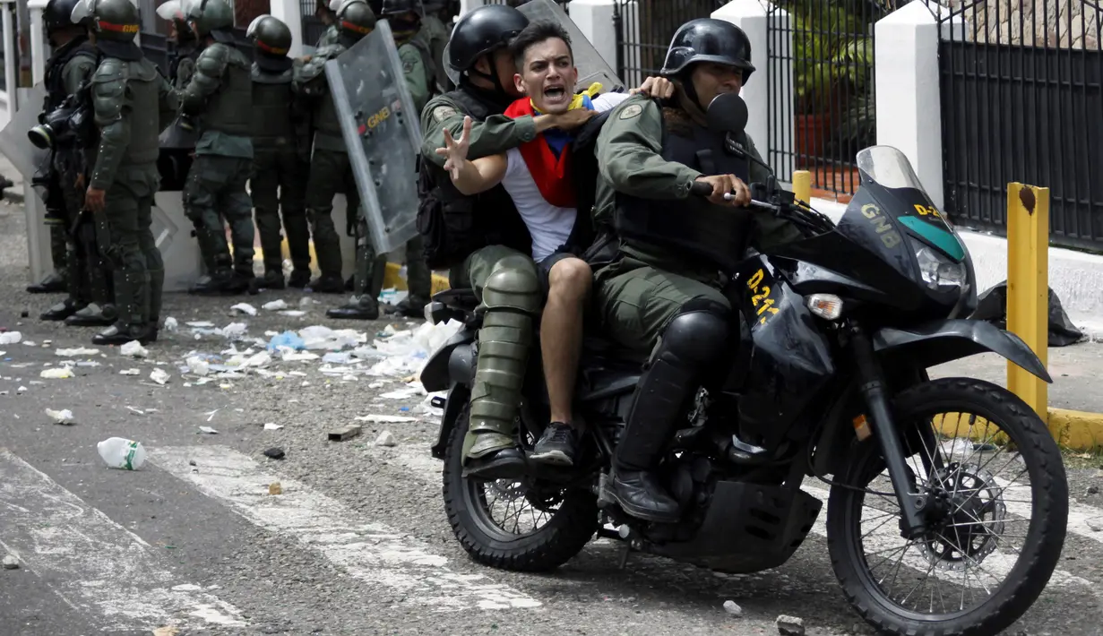 Seorang demonstran dibawa petugas saat bentrok di San Cristobal, Venezuela (26/10). Unjuk rasa bertajuk "Ambil Alih Venezuela" ini menuntut adanya referendum untuk melengserkan Maduro. (REUTERS/Carlos Eduardo Ramirez)