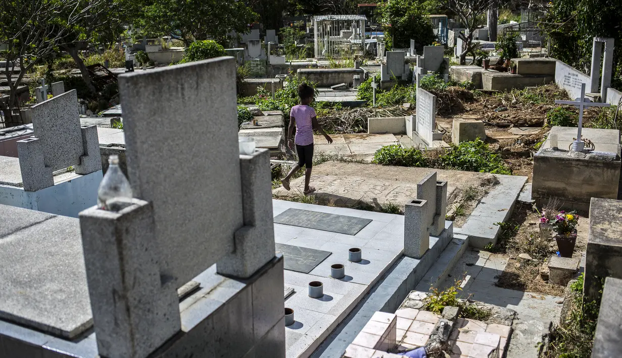Seorang gadis berlari di tengah kuburan di Pemakaman Umum Selatan di Caracas, pada 16 Februari 2021. Makam yang dirusak telah menjadi rumah bagi banyak tunawisma di Venezuela. (Pedro Rances Mattey / AFP)