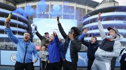 Para fans dan pendukung Manchester City bersorak sambil menyalakan flare merayakan keberhasilan timnya memastikan merebut gelar juara Liga Inggris 2020/2021 di luar Etihad Stadium, Selasa (11/5/20221) sesaat setelah kekalahan Manchester United 1-2 oleh Leicester City di Old Trafford. (AP/Jon Super)