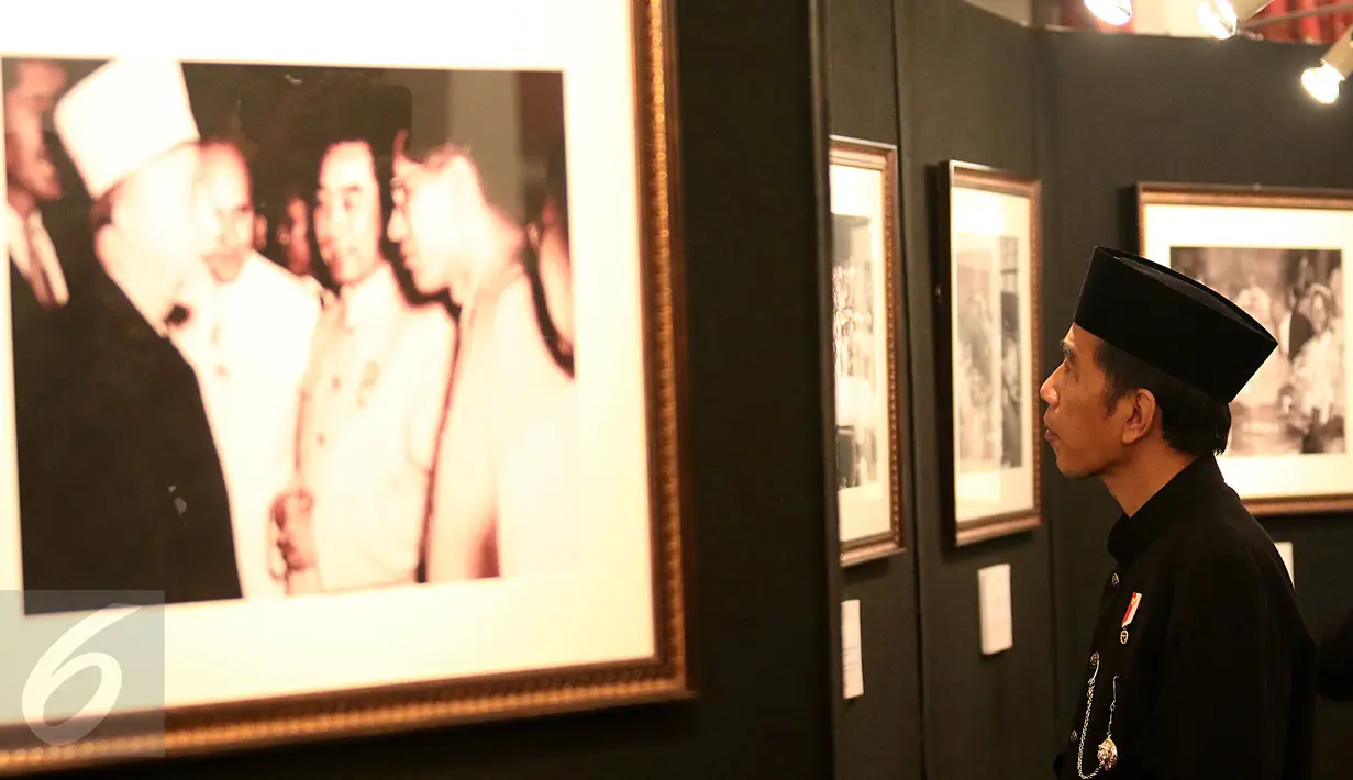 Presiden Joko Widodo (Jokowi) mengamati gambar pada pameran foto dalam rangka peringatan Konferensi Asia Afrika (KAA) ke-62 di Istana Negara, Jakarta, Selasa (18/4). Pameran foto itu berisi kegiatan KAA 62 tahun yang lalu. (Liputan6.com/Angga Yuniar)