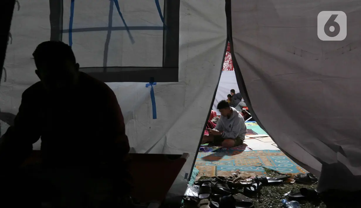 Warga terdampak gempa saat mengungsi di posko pengungsian di Taman Prawatasari, Kabupaten Cianjur, Jawa Barat, Selasa (22/11/2022). Gubernur Jawa Barat Ridwan Kamil menyebut, sebanyak 14 posko pengungsian didirikan untuk memfasilitasi warga berjumlah 13.784 pengungsi yang terdampak gempa berkekuatan 5,6 SR di Kabupaten Cianjur. (Liputan6.com/Herman Zakharia)
