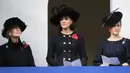 Kate Middleton berdiri di antara Putri Sophie dan Putri Alexandra menghadiri upacara Remembrance Sunday Service di London, Minggu (12/11). Kate juga mengenakan oversize black hat dengan dengan ornamen berbentuk hati. (TOLGA AKMEN / AFP)