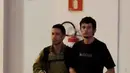 Terduga teroris berjalan dikawal oleh polisi di hanggar Polisi Federal Brasil di bandara di Brasil, (21/7). Kepolisan Brasil menangkap 10 orang amatiran yang disebut seakan-akan telah menyatakan kesetiannya kepada ISIS.( AFP PHOTO/Evaristo SA)