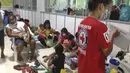Keluarga tinggal di pusat evakuasi sementara di provinsi Catanduanes, Filipina timur, Minggu (1/11/2020). Badan cuaca Filipina mengatakan Topan Goni diperkirakan menghantam ujung tenggara Pulau Luzon pada Minggu (1/11/2020) dengan kecepatan angin 205 kilometer per jam. (Philippine Red Cross via AP)