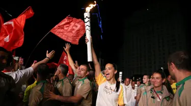 Supermodel Adriana Lima bersorak sambil membawa obor pada malam penyambutan Olimpiade Rio 2016 di Maua Square Rio de Janeiro, Brasil, Kamis (4/8). (REUTERS / Pilar Olivares)
