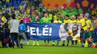 Para pemain Brasil membentangkan spanduk dukungan untuk Pele yang sedang sakit pada akhir pertandingan sepak bola babak 16 besar Piala Dunia 2022 antara Brasil dan Korea Selatan di Stadium 974, Doha, Qatar, 5 Desember 2022. (AP Photo/Andre Penner)