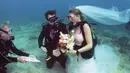 Pendeta John Hauk (kiri) membacakan sumpah pernikahan di bawah laut kepada pasangan Sersan Thomas Mould (tengah) dan Sandra Hyde dari Key Largo, Fla di Florida Keys National Marine Sanctuary (21/12). (Frazier Nivens/Florida Keys News Bureau via AP)