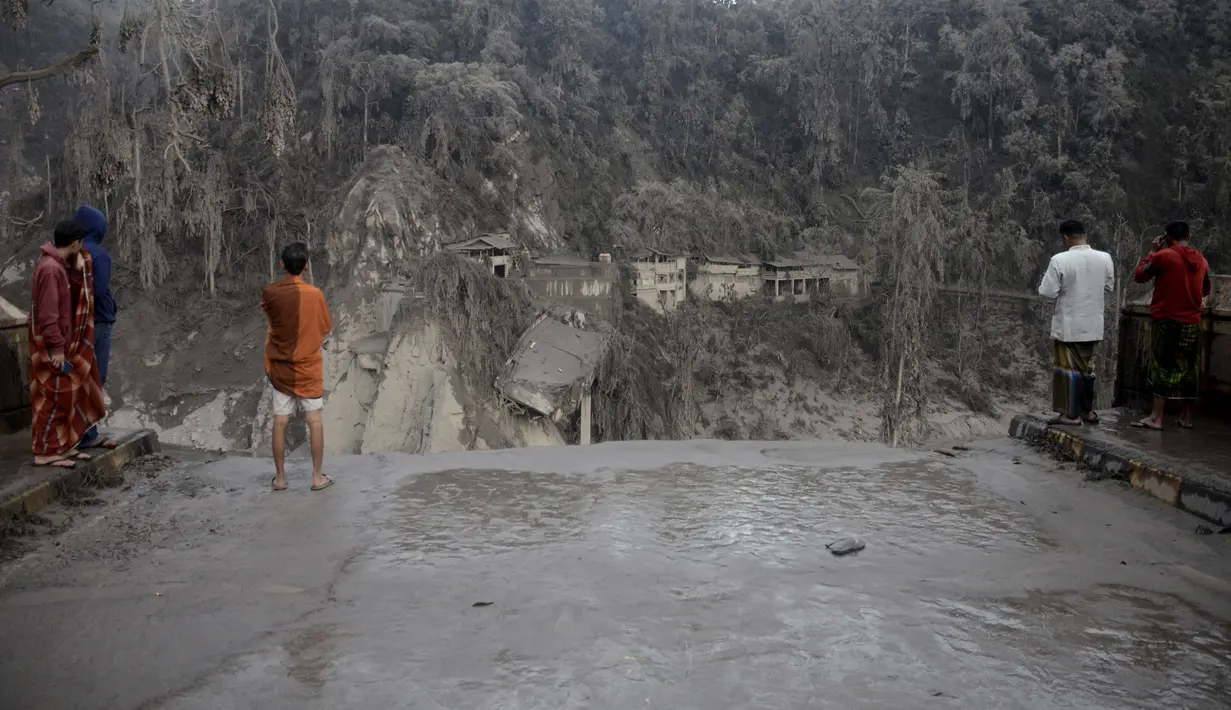 Warga melihat jembatan yang rusak akibat abu vulkanik pascaerupsi Gunung Semeru di Lumajang, Jawa Timur, 5 Desember 2021. Sebanyak 14 orang meninggal dunia dan 69 mengalami luka-luka akibat erupsi Gunung Semeru. (AP Photo/Hendra Permana)