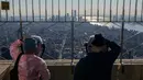 Pengunjung melihat pemandangan dari lantai 86 Empire State Building, New York pada 9 November 2021. Turis asing yang mendatangi Amerika Serikat disambut kembali ke New York City untuk pertama kalinya dalam 20 bulan setelah pembatasan perjalanan pandemi Covid-19 dicabut. (ANGELA WEISS / AFP)