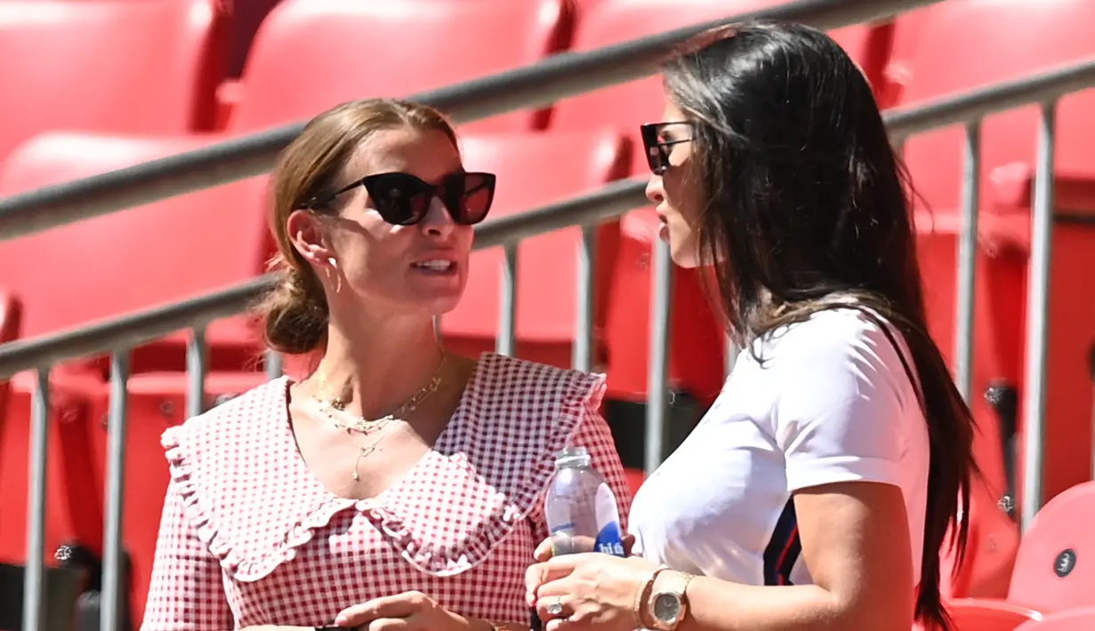 Annie Kilner, tunangan pemain Inggris Kyle Walker (kanan) berbincang Coleen Rooney, istri mantan pemain Inggris Wayne Rooney pada grup D Euro 2020 antara Inggris melawan Kroasia di stadion Wembley, London (13/6/2021). Annie tampil mengenakan jersey Inggris dan kacamata hitam. (AFP/Pool/Glyn Kirk)