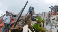 Warga memeriksa rumah-rumah yang rusak akibat gempa di Mamuju, Sulawesi Barat, Indonesia, Jumat (15/1/2021). Gempa yang berpusat di timur laut Majene tersebut terjadi pada Jumat (15/1/2021) pukul 02.28 Wita. (AP Photo/Rudy Akdyaksyah)