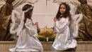 Anak-anak berpakaian seperti malaikat berdoa di depan altar pada tengah malam Natal di Katedral St. Ibu Teresa di ibukota Kosovo, Pristina (24/12). (AP Photo / Visar Kryeziu)