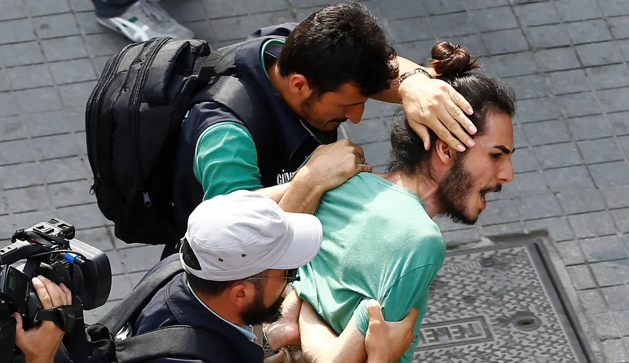Polisi berpakaian preman menahan aktivis LGBT ketika mereka mencoba melancarkan pawai tahunan LGBTI, di Istanbul, Minggu (26/6). Satu pekan sebelumnya, pemerintah Turki telah mengeluarkan larangan menggelar pawai tahunan LGBTI. (REUTERS/Osman Orsal)