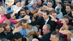 Presiden Suriah, Bashar al-Assad bersalaman dengan para pendukungnya usai melaksanakan salat Idul Adha di Masjid Agung Qara, di wilayah Qalamoun di pinggiran ibukota Suriah Damaskus (1/9). (AFP Photo/Sana/Handout)
