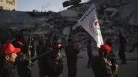 Militan Front Demokratik untuk Pembebasan Palestina (DFLP) berbaris melewati sebuah bangunan yang hancur oleh serangan udara selama parade di jalanan Kota Gaza, Selasa (8/6/2021). Gencatan senjata mengakhiri perang 11 hari antara Hamas sebagai penguasa Gaza dengan Israel. (AP Photo/Felipe Dana)