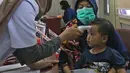 Petugas medis mengecek suhu tubuh seorang anak melalui Rail Clinic di stasiun kereta Depok, Jumat (6/3/2020).  PT KAI Daop 1 melakukan kegiatan  sosialisasi mengenai penyebaran virus corona dengan menghadirkan kereta kesehatan Rail Clinic. (Liputan6.com/Herman Zakharia)