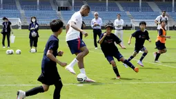Pemain Paris Saint-Germain (PSG), Kylian Mbappe bermain sepak bola bersama anak-anak saat memberikan pelatihan di Jepang. (AP/Eugene Hoshiko)