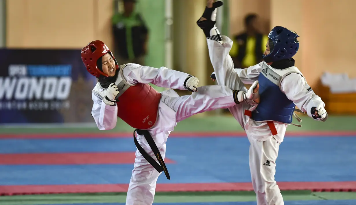 Dua peserta perempuan saat bertarung dalam Kejuaraan Terbuka Taekwondo di Banda Aceh (17/7/2019). Ratusan peserta mengikuti turnamen yang memperebutkan Piala Pemerintah Aceh. (AFP Photo/Chaideer Mahyuddin)