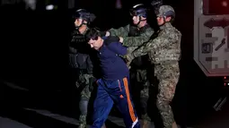 Bos narkoba Joaquin "El Chapo" Guzman berjalan saat dikawal ketat oleh tentara di kantor Kejaksaan Agung, Meksiko (8/1/2016). Joaquin "El Chapo" Guzman melarikan diri dari penjara melalui terowongan yang ia buat pada 11 Juli 2015. (REUTERS/Tomas Bravo)